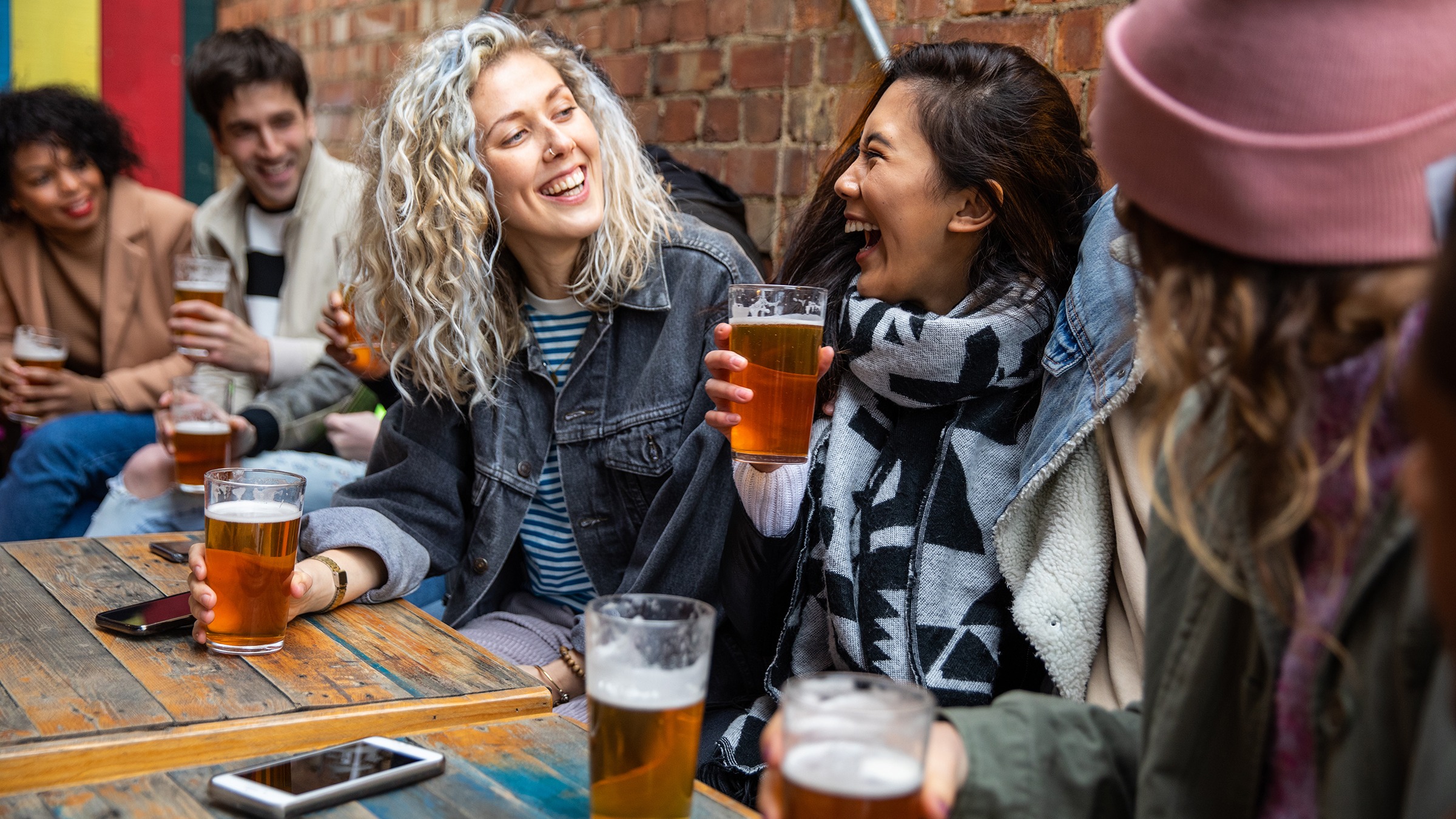 A group of friends, including women, enjoying drinks at an outdoor setting, highlighting social aspects of women and alcohol consumption.